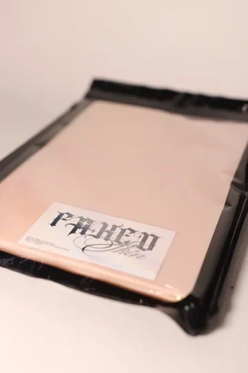 Angled front view of the packaged FAKED SKIN tattoo practice pad