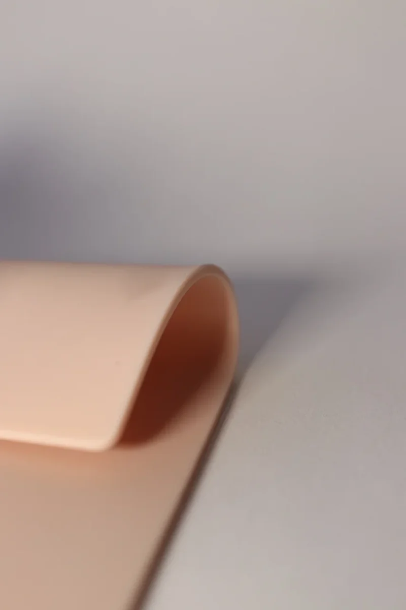 Side view of a curved flesh-tone Faked Skin practice pad on a light surface